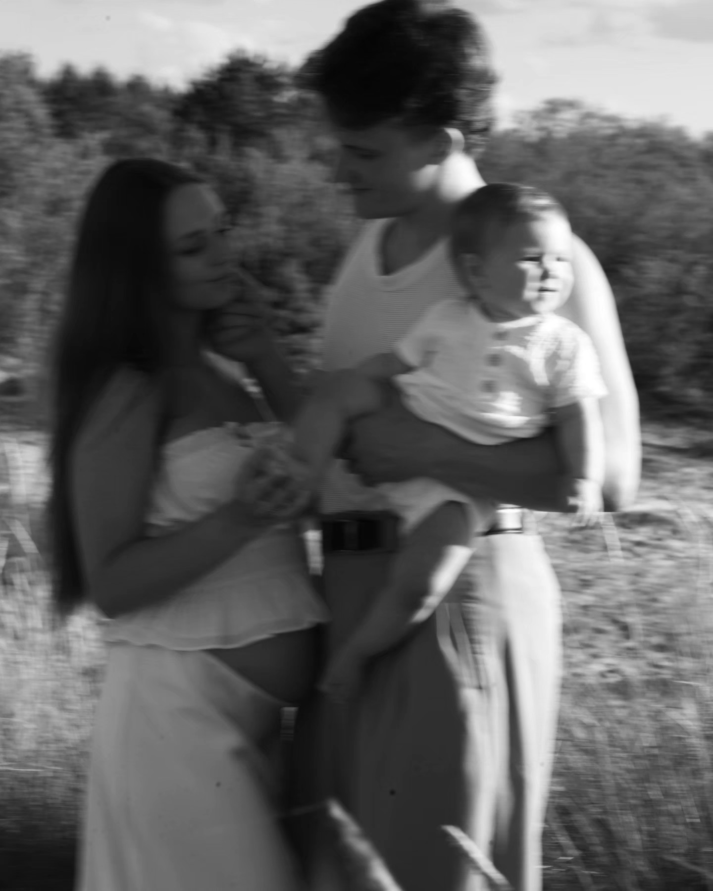 Ģimene laukā – mamma, tētis un mazulis melnbaltā bildē